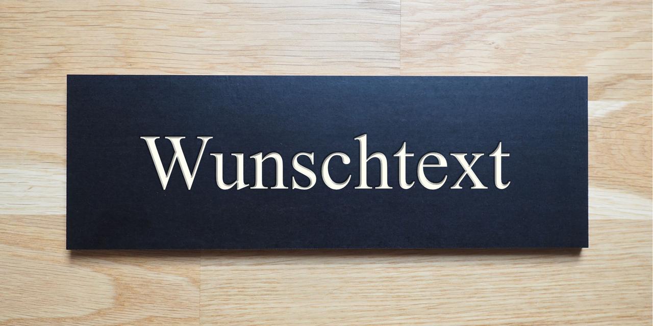 Schwarzes Schild, die Gravur zeigt den hellen Holzkern